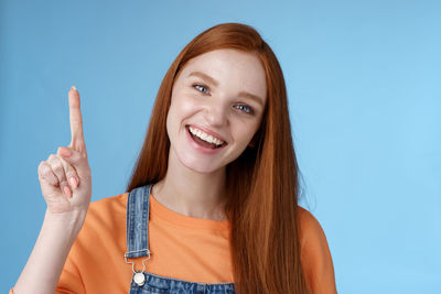 Young woman pointing against blue background