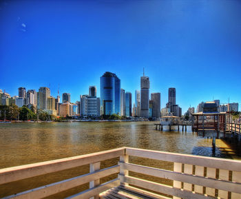 River and buildings against clear blue sky