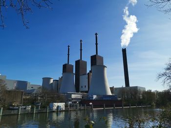 Smoke emitting from factory against sky