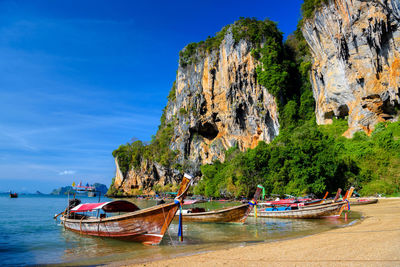 Boats moored on rock by sea against sky