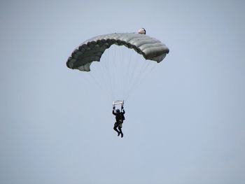 Low angle view of man paragliding against clear sky