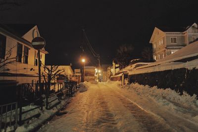 Street amidst illuminated buildings during winter at night