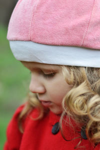 Cute girl with curls in a red coat looks away