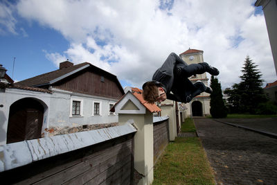 Young woman outside house against sky