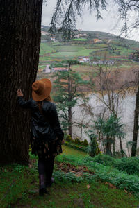 Rear view of woman standing on field by trees in forest