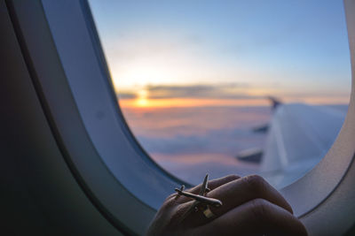 Cropped image of hand on window in airplane