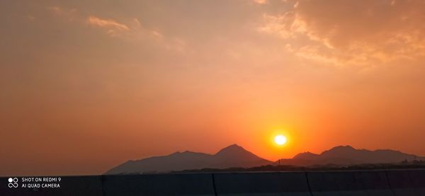 Scenic view of silhouette mountains against romantic sky at sunset