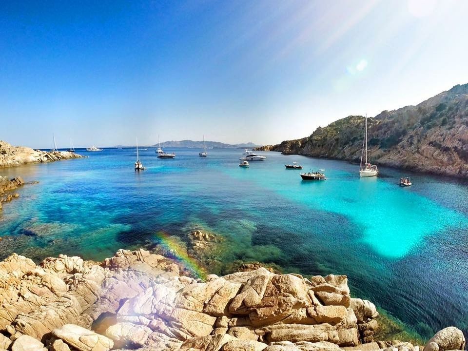 nautical vessel, transportation, water, mode of transport, boat, blue, sea, moored, tranquil scene, scenics, tranquility, rock - object, beauty in nature, nature, clear sky, rock formation, travel, sunlight, rock, day