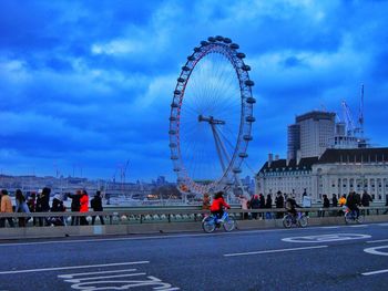 People on bicycle in city against sky