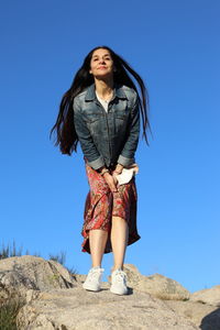 Full length of woman standing against blue sky