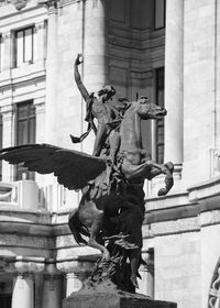 Low angle view of statue against palacio de bellas artes on sunny day