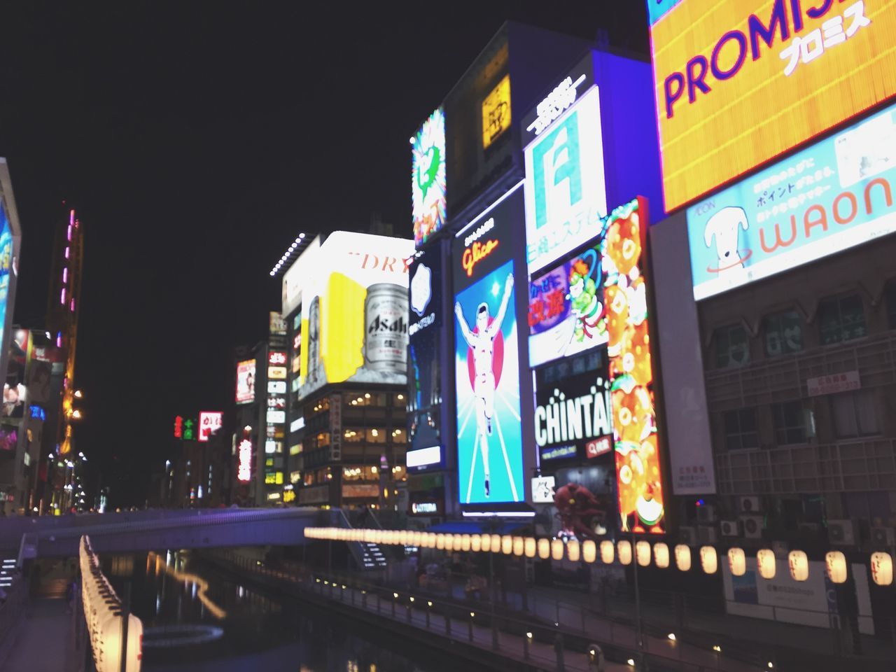 illuminated, architecture, built structure, building exterior, night, city, text, western script, building, low angle view, street, sky, outdoors, no people, communication, city life, residential building, street light, lighting equipment, light - natural phenomenon