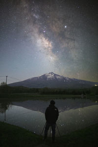 Rear view of man walking on road against sky at night