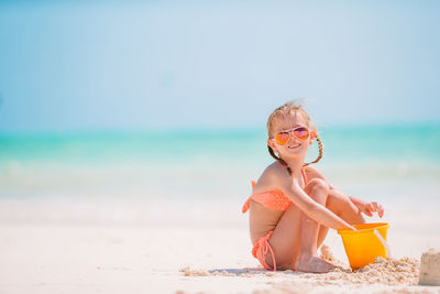 Portrait of young woman in bikini standing at beach