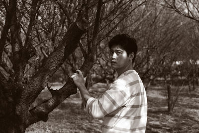 Side view portrait of boy on tree trunk