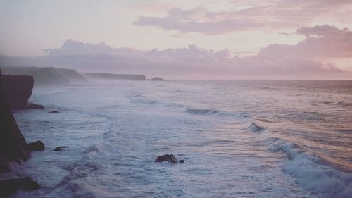 Scenic view of sea against cloudy sky during sunset