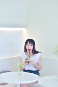 Portrait of young woman sitting on table