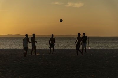 Young people playing beach soccer during sunset at ribeira beach in salvador, bahia, brazil.