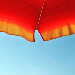 Low angle view of parasol against clear blue sky