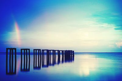 Wooden posts amidst sea against sky