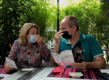 Couple wearing mask sitting at cafe