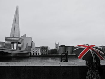 Rear view of woman with umbrella on promenade against sky