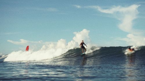 Man surfing on sea against sky