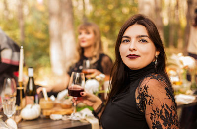 Portrait of a young woman with drink on table at restaurant