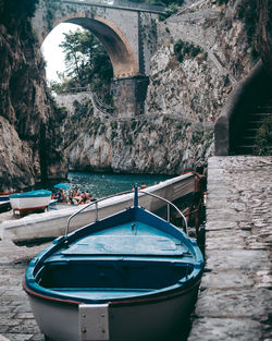 View of rowboat against stone wall by canal