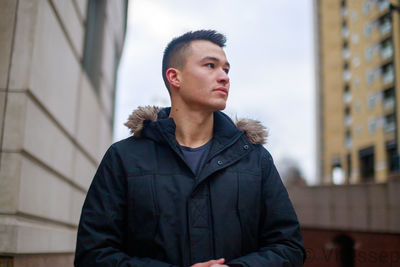 Young man looking away while standing outdoors