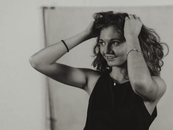 Portrait of young woman standing against wall