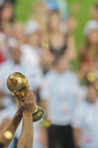 Cropped hands of people holding trophy on field