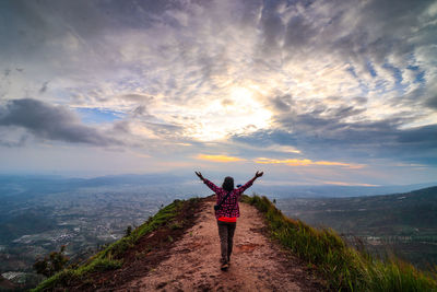 Rear view of woman standing on mountain against sky