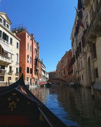 Boat in canal amidst buildings against sky in city