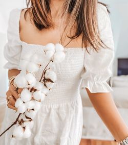 Midsection of woman standing against white curtain at home