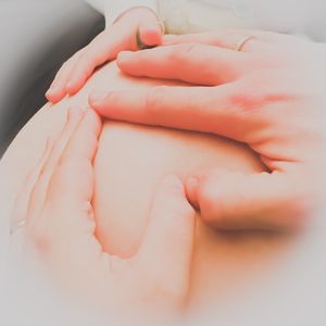 Close-up of people hands on pregnant woman abdomen