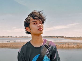 Portrait of young man looking away against sky