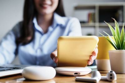 Midsection of woman using mobile phone while sitting on table