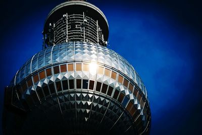 Low angle view of illuminated tower against blue sky