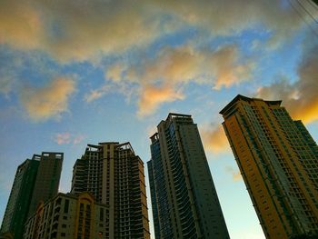 Low angle view of skyscrapers against cloudy sky