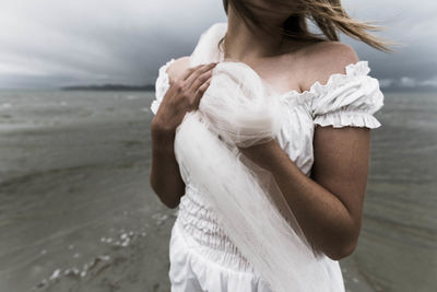 Midsection of bride standing at beach