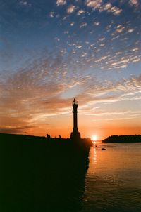 Silhouette lighthouse against sky during sunset