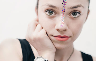 Close-up portrait of young woman with glitter on face