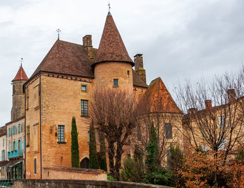 Old building by trees against sky