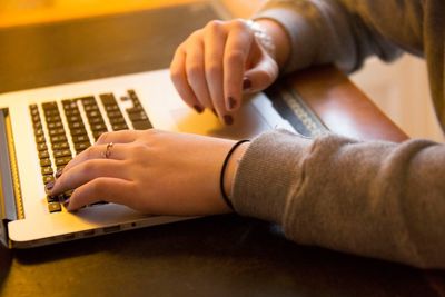 Cropped image of woman using laptop on desk