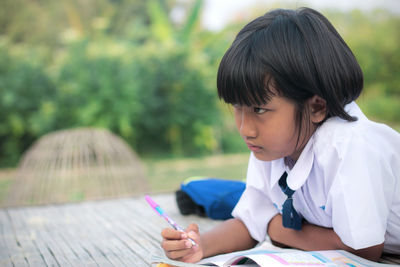 Cute girl studying while lying outdoors