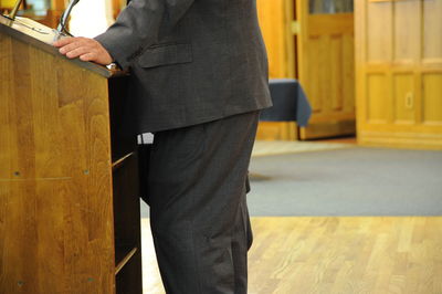 Midsection of man holding umbrella while standing on wood