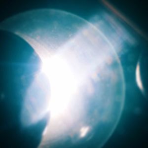 Low angle view of sun shining through blue sky