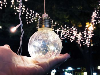 Close-up of hand holding illuminated light bulb