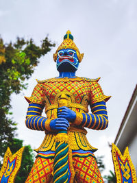 Low angle view of statue against temple building against sky